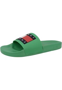 Sandale glissante verte en plastique lisse avec une large sangle présentant un design de logo multicolore et le texte "TOMMY JEANS."