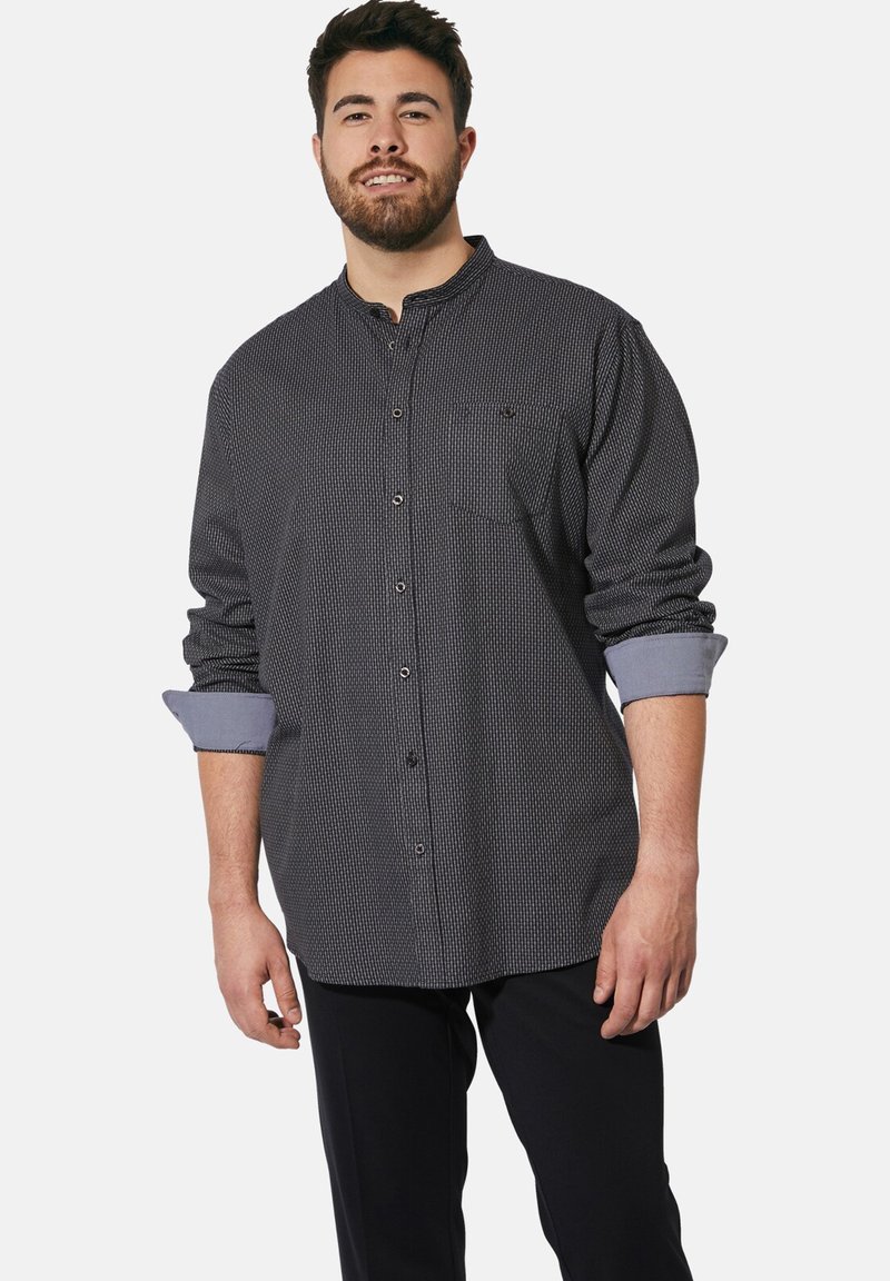 Schwarz-weißer karierten Hemd mit langen Ärmeln, Knopfverschluss und einer Brusttasche; hochgerollte hellblaue Bündchen setzen einen Kontrast.