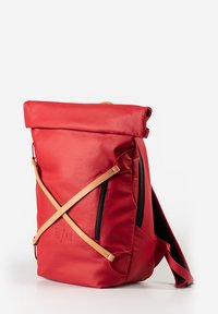 Zaino arrotolabile rosso realizzato in pelle liscia, caratterizzato da cerniere nere, un design con tracolla e una forma snella.