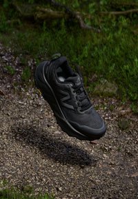 Zwarte trailrunschoen met een bovenwerk van mesh, textuurpatronen en rubberen zool. Voorzien van een versterkte neus en een heel-lus.