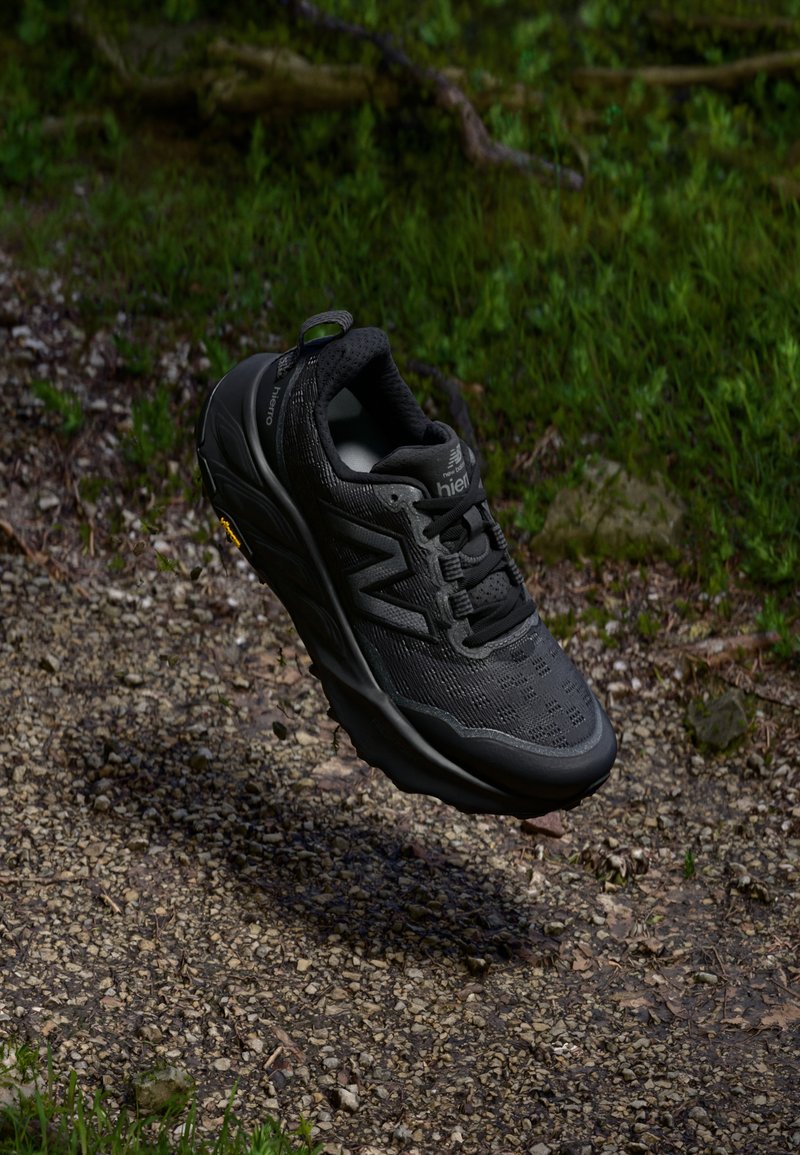 Zwarte trailrunschoen met een bovenwerk van mesh, textuurpatronen en rubberen zool. Voorzien van een versterkte neus en een heel-lus.