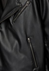 Crna kožna motos jakna s višestrukim zatvaračima, robusnom teksturom i klasičnim asimetričnim ovratnikom.