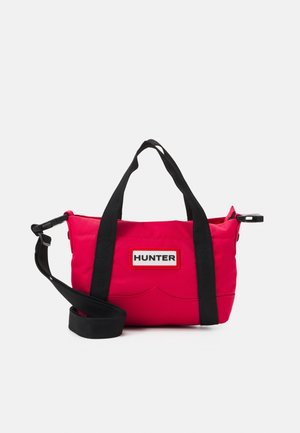 Kirkkaanpunainen Hunter-käsilaukku mustilla kahvoilla ja säädettävällä olkahihnalla, keskitetty yksinkertaiselle valkoiselle taustalle.