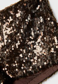 Čierny a medený flitrový materiál s hladkou textúrou; tesne usporiadané flitre vytvárajú lesklý povrch, ktorý zvyšuje odraz svetla.