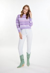 Maglione viola a fantasia con scollatura rotonda, abbinato a jeans blu chiaro e stivali alla caviglia in stile western verdi con ritagli.