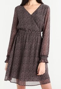 Vestido negro con flores, de corte envolvente y mangas largas, con cintura fruncida y un dobladillo fluido. Tejido ligero y transparente con un patrón delicado.