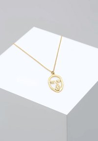 Goldfarbene Metalkette mit einem minimalistischen Anhänger in Form eines Gesichtes, der über ausgeklügelte Gesichtszüge verfügt und an einer feinen Kette hängt.
