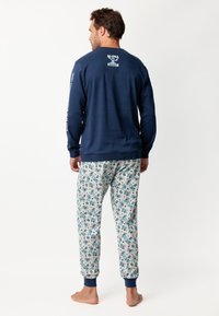 Camisa de manga larga en color azul marino con estampado de "Aloha Stitch"; pantalones de pijama estampados en tejido ligero con diseños en azul y rosa; con tobillos ajustados.