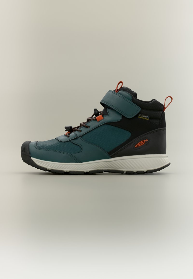 Μπότες πεζοπορίας μεσαίου ύψους με επάνω μέρος σε σκούρο τιρκουάζ, μαύρες λεπτομέρειες, υφασμένο σχέδιο, ανθεκτική σόλα από καουτσούκ και ρυθμιζόμενο λουράκι βέλκρο.