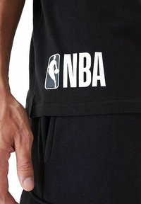 Schwarzes NBA-T-Shirt mit einem großen weißen Logo und der Silhouette eines Basketballspielers auf der Seite. Weicher Baumwollstoff mit lässiger Passform.
