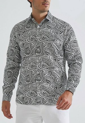 Chemise à manches longues en noir et blanc présentant des motifs tourbillonnants complexes, des formes géométriques et un col classique.