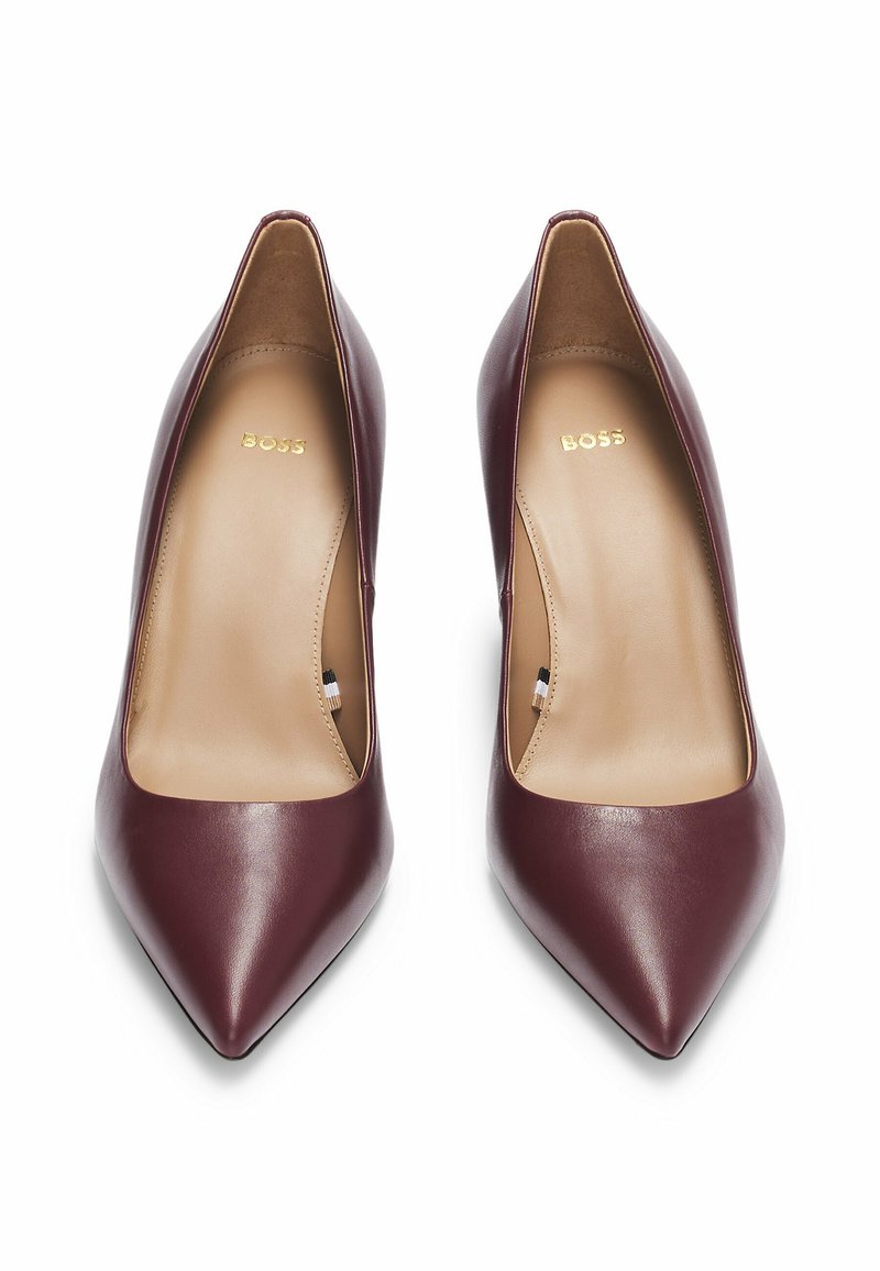 Décolleté in pelle bordeaux con punta affusolata e finitura liscia. L'interno è rivestito in beige, con un discreto logo del brand in oro.