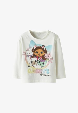 Chemise blanche à manches longues avec une fille de dessin animé portant un serre-tête avec des oreilles de chat, entourée de quatre personnages animaliers colorés, texte "Gabby's Dollhouse" en dessous.