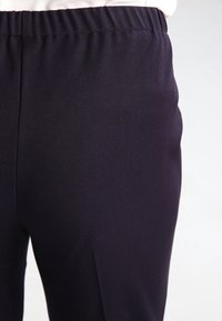Pantalon bleu marine à texture lisse, doté d'une ceinture élastique et d'une coupe fuselée. Aucun motif visible ni détail de quincaillerie.