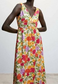 Robe maxi fleurie avec un col en V, ornée de fleurs rouge vif, orange, jaune et violet sur un fond clair et dotée d'une taille élastique.