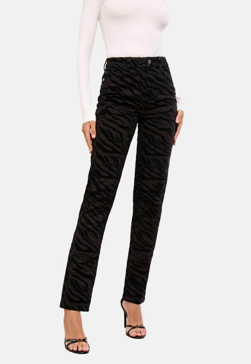 Mustad corduroy püksid, millel on tõstetud musta tiigri triibud, sirge lõige ja viie taskuga disain, koos rihmadega kontsakingadega.