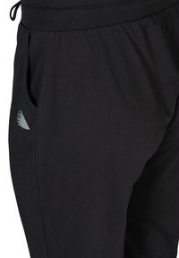 Pantaloni jogger neri realizzati in un morbido e elasticizzato tessuto, dotati di cintura elastica e tasche laterali. Un logo bianco discreto è visibile sul lato sinistro.