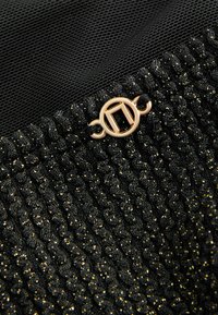 Tissu noir texturé avec un éclat doré, comportant un design drapé et un accent de quincaillerie circulaire métallisé.