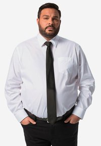 Witte dress shirt met een zak, zwarte stropdas en zwarte broek. Beschikt over lange mouwen met verstelbare manchetten en een nette, klassieke pasvorm.