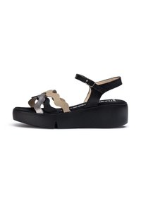Sandalias de plataforma negras con un diseño de tira texturizada, que presenta acentos beige con bordes ondulados y una correa en el tobillo ajustable.