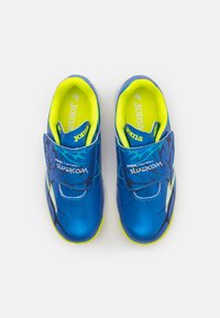 Pantofi sport albaștri cu un upper sintetic texturat, interior galben neon și o curea Velcro; prezintă accente negre și un design cu model.
