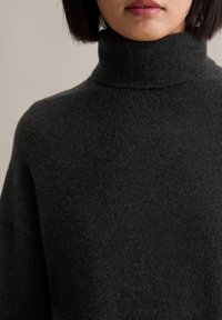 Dunkelgrauer Rollkragenpullover aus weichem, strukturiertem Strickstoff; mit einem hohen Kragen und lockerer Passform. Keine sichtbaren Muster oder Verzierungen.