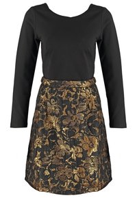 Haut noir à manches longues avec une jupe à motif floral doré et noir attachée, créant une robe une pièce avec une taille cintrée.