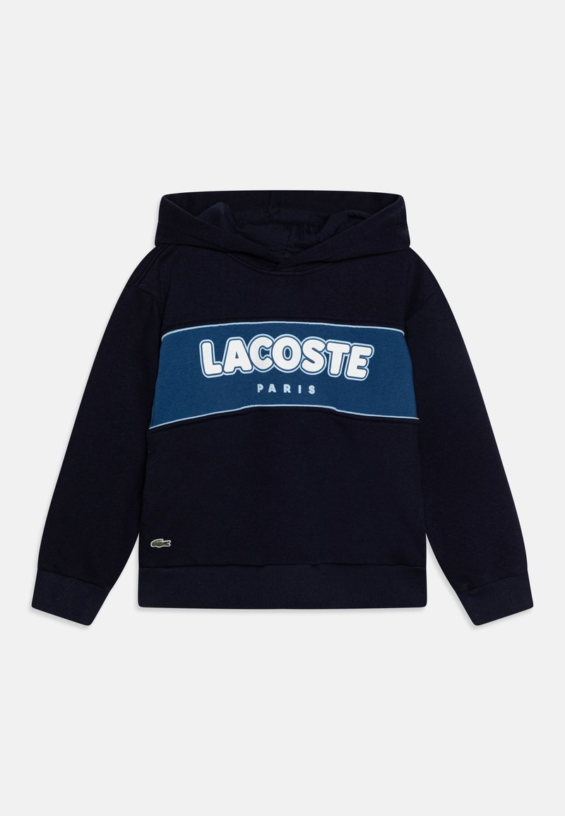 Sweat-shirt à capuche bleu marine avec un grand logo blanc "LACOSTE PARIS" sur la poitrine et un petit emblème de crocodile vert sur l'ourlet.