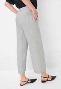 Lichtgrijze linnen broek met een ontspannen pasvorm, cropped lengte en twee achterzakken. Gecombineerd met zwarte slingback flats.