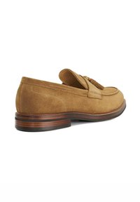Suede loafers in light brown with a rounded toe and decorative tassels. Features a brown stacked heel and contrasting stitching detail.