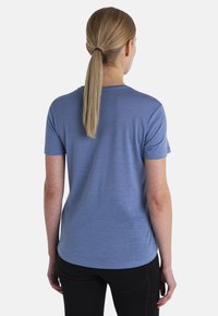 Camisa de tirantes corta de color azul, confeccionada con un tejido suave, con un cuello redondo y un corte relajado, con detalles de costura visibles y una textura suave.