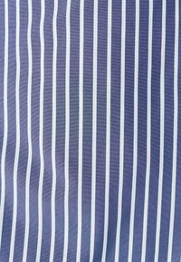 Pruhovaná tkanina s alternativními námořnickými a bílými svislými pruhy, s hladkou strukturov a rovnoměrným rozestupem mezi pruhy.