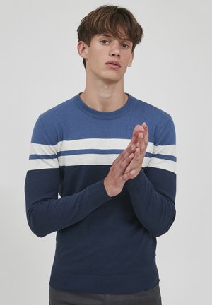 Maglione blu navy con strisce orizzontali azzurro chiaro e bianche. Collo rotondo, polsini e orlo aderenti, texture a coste. Design semplice, materiale morbido.