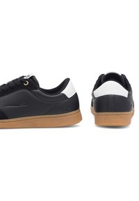 Mustad nahast spordijalatsid valge kandilise detaili ja kuldsete silmadega. Kummiastmega tallal on tekstuur, mis tagab haarde. Klassikaline madala topiga disain.