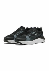 Sneaker sportive nere e grigie con tomaia in rete, sovrapposizioni testurizzate, suola bianca e logo PUMA sulla linguetta e sul lato. Punta arrotondata e design con lacci.