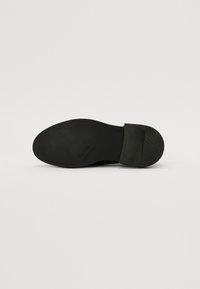 Črna gumijasta podplat čevlja z elegantnim, ravnim dizajnom, zaobljenim nosom in teksturiranim oprijemom. Ima gladek zaključek in minimalno označevanje.