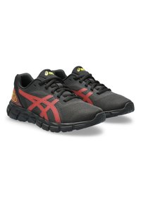 Baskets de sport noires avec des accents rouges, dessus en mesh, bout rond, semelle rembourrée et lacets noirs. Dispose d'un logo sur la languette et sur le côté.