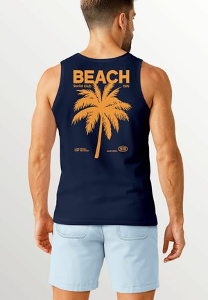 Marinefarbener Tanktop mit einem orangefarbenen Palmbaum-Graphic, dem Text "BEACH Social Club 1976" und zusätzlichen Branding-Details am unteren Rand.
