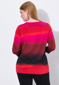 Langärmliges Oberteil mit einem Farbverlaufsmuster von Rot und Rosa, das in Schwarz übergeht. Hergestellt aus glattem Stoff mit einem runden Halsausschnitt.