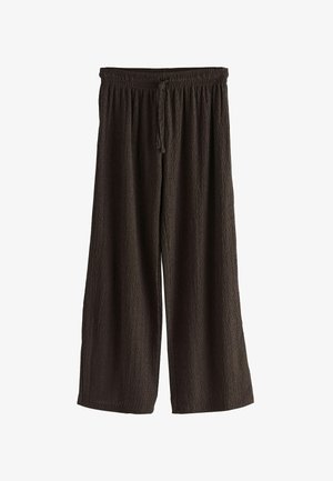 Platas kājas bikses no teksturēta auduma tumši brūnā krāsā. Iezīmēta ar elastīgu jostas vietu un auklu, lai pielāgotu izmēru.