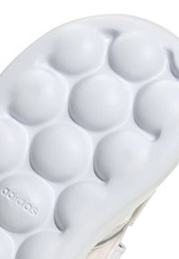 Bijela potplatica tenisice s okruglim uzorcima profila i otisnutim "adidas" logom. Gladak tekstura s blago sjajnom završnom obradom.