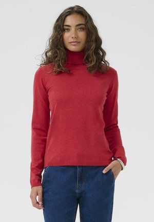 Roter Rollkragenpullover aus weichem Material, mit langen Ärmeln und taillierter Passform, kombiniert mit blauen Hochbundjeans.