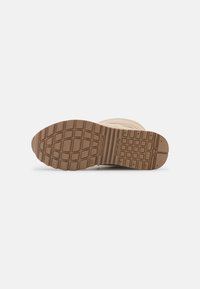 Suola di sneaker con una suola in gomma marrone texture, dotata di un grip motivo e una leggera curva alla punta per una trazione migliorata.