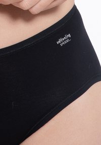 Svart bomullsstringtrosor med en mjuk elastisk midja som har en liten logotyp "mjukt känsla" och "SPEIDEL" tryckt i vitt.