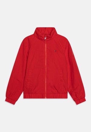 Veste rouge zippée avec col montant, poignets élastiques, poches latérales et petit logo sur la poitrine gauche, présentée sur fond blanc.