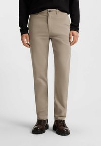 Chinos beige realizzati in morbido cotone misto. Design con gamba dritta, passanti per cintura, tasche frontali e una texture sottile. Abbinati a stivali marroni con lacci.
