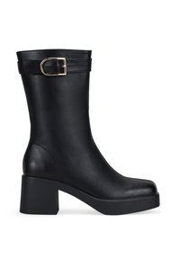 Botín de cuero negro hasta el tobillo con un tacón cuadrado, que presenta un detalle de hebilla dorada y una textura suave. Diseño elegante y ajustado con puntera redonda.