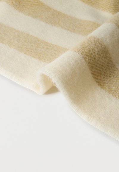 Μαλακό μάλλινο ύφασμα με μπεζ και κρεμ ευρείες οριζόντιες ρίγες, απαλά διπλωμένο σε λευκή επιφάνεια.