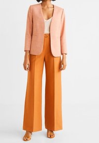 Peach-colored blazer with a minimalist design, paired with wide-legged orange trousers. Smooth fabric with tailored fit and long sleeves.