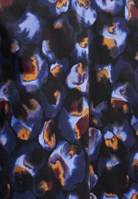 Mönstrad tyg med stora abstrakta fläckar i nyanser av blått, mörklila och orange mot en svart bakgrund. Mjuk textur.